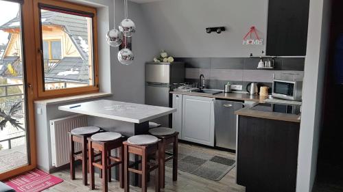 a kitchen with a table and some stools in it at Apartament Podkowa z widokiem na Giewont in Kościelisko