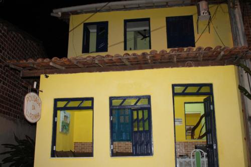una casa amarilla con ventanas negras y techo en Pousada da Lurdinha, en Lençóis