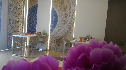 a room with two tables and chairs and purple flowers at Luxury B&B Coccolhouse in San Cesario di Lecce