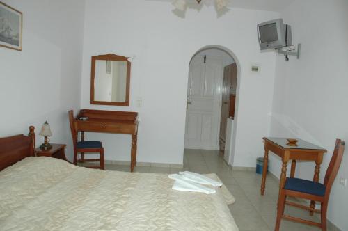 a bedroom with a bed and a desk and a mirror at Hotel Filoxenia in Aegiali