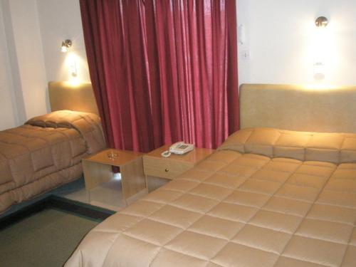 a bedroom with a bed and a table and red curtains at Hotel Niki in Nafpaktos