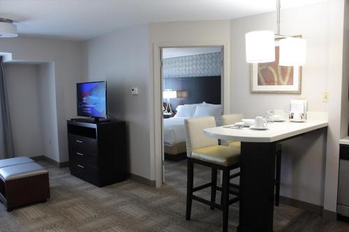 a hotel room with a bed and a desk with a television at Staybridge Suites Miamisburg by IHG in Miamisburg