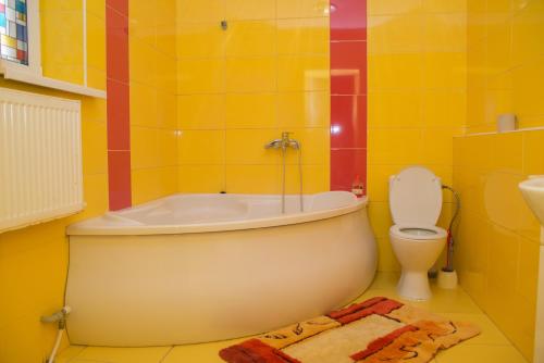 a yellow bathroom with a tub and a toilet at Апельсин in Myrhorod