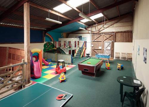 a play room with a pool table and play equipment at Long Barn Holiday Cottages in Newton Abbot