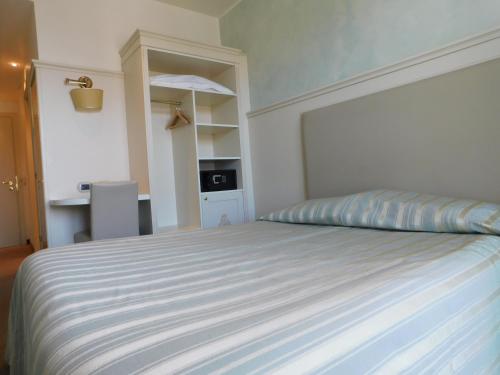 a bedroom with a bed with a striped bedspread at Palace Hotel & SPA La CONCHIGLIA D' ORO in Vicenza