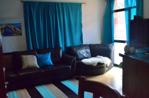 a living room with two leather couches and blue curtains at Residencia Santiago Mallorca in Cala Figuera