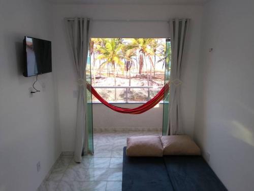 uma sala de estar com uma janela com um cobertor vermelho em Canto do Sabiá Apart Hotel em Barra de Camaratuba
