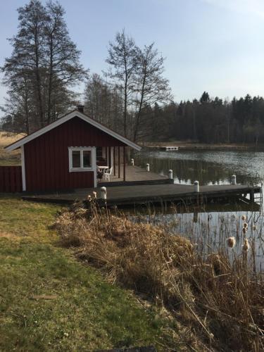 a small cabin on a dock next to a lake at Sjöstugan in Söderköping