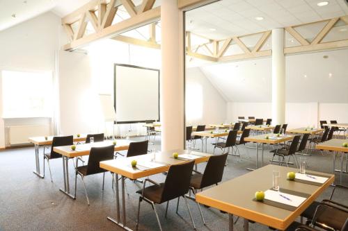 a classroom with tables and chairs and a projection screen at Golfhotel Fahrenbach in Tröstau