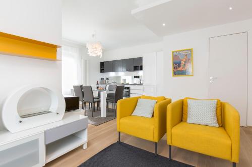 a living room with two yellow chairs and a kitchen at Maraini Apartments by Quokka 360 - strategic location near Lugano station in Lugano