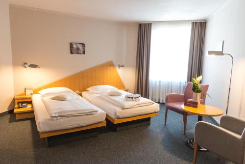 um quarto de hotel com duas camas e uma cadeira em Golfhotel Fahrenbach em Tröstau