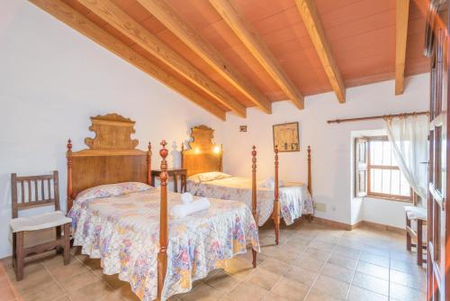 a bedroom with two beds and a wooden ceiling at Ca Na Carme (Alaronera) in Alaró