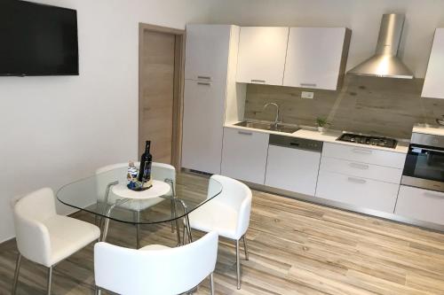 a kitchen with a glass table and white chairs at Apartments Villa Stivan in Solin