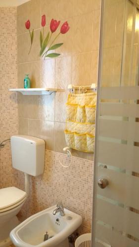 a bathroom with a toilet and a sink with flowers on the wall at Casa Vacanze Arba Girasole in Girasole