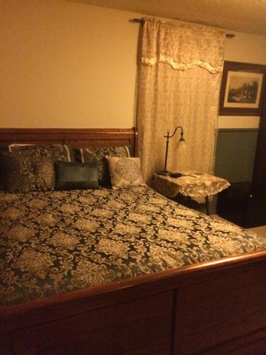 ein Schlafzimmer mit einem Bett und einem Tisch mit einer Lampe in der Unterkunft Main Street Bed & Breakfast in Glasgow