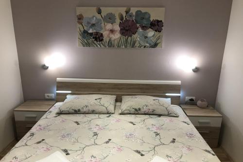 a bedroom with a bed with two pillows and a painting at Apartments Villa Stivan in Solin