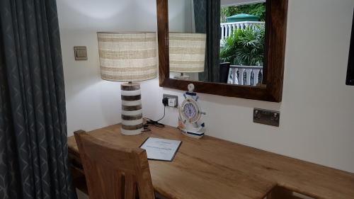 a lamp on a wooden table with a mirror at Drake Seaside Studio Apartments in Bel Ombre