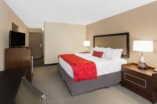 a hotel room with a bed and a flat screen tv at Ramada by Wyndham Des Moines Airport in Des Moines
