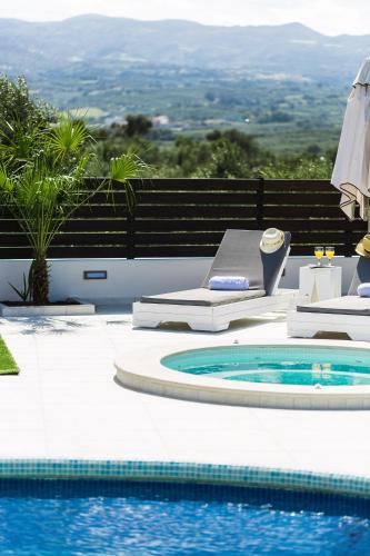 a swimming pool with a table and an umbrella at Caramel Villa, with 40m2 Pool & Spa Whirlpool, By ThinkVilla in Panormos Rethymno