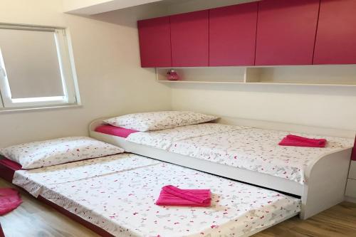 two twin beds in a room with red cabinets at Apartments Villa Stivan in Solin