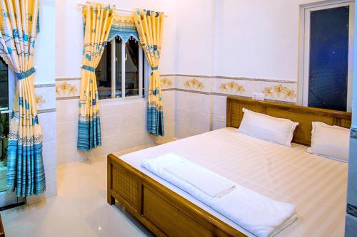 a bedroom with a bed with yellow and blue curtains at Motel Thuyền & Biển in Ly Son
