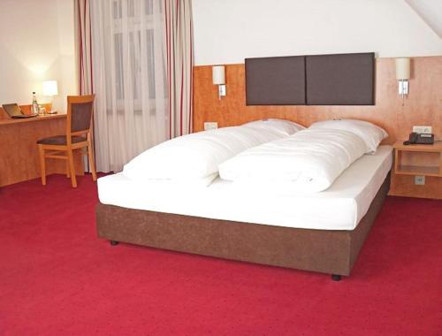 Cama grande en habitación con alfombra roja en Hotel Neuwirtshaus - Superior, en Stuttgart