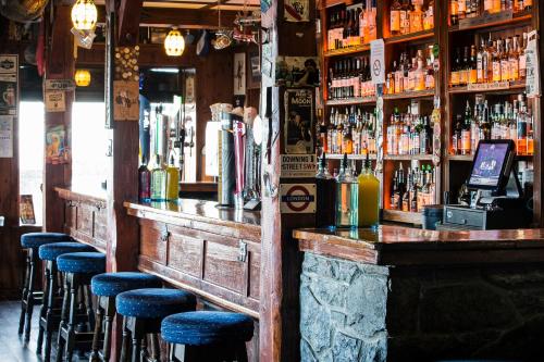 a bar with blue stools in a room with alcohol at Maddens Bridge Bar & Guesthouse in Bundoran