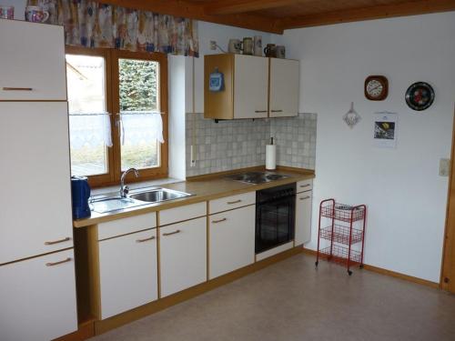 uma cozinha com armários brancos e um lavatório em Familie Meimer em Höfing