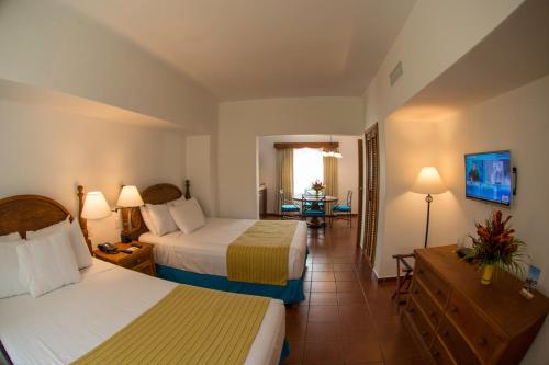 Amatique Bay Hotel في بويرتو باريوس: غرفة فندقية بسريرين وطاولة