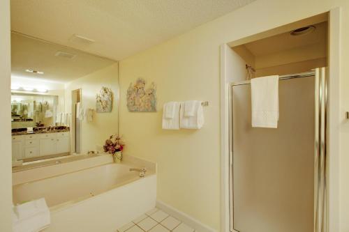 a bathroom with a tub and a shower with a mirror at Tides at Topsl by Panhandle Getaways in Destin