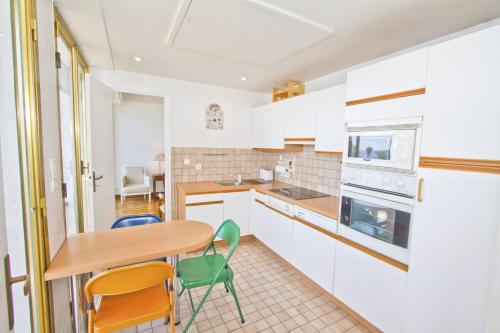 une cuisine avec des armoires blanches et une table et des chaises dans l'établissement PROMENADE HOLIDAY - ORIENT & SEA, à Nice