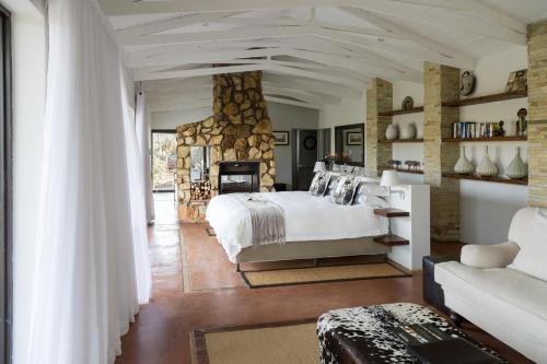a bedroom with a bed and a stone wall at Hopewell Private Game Reserve in Buyskloof