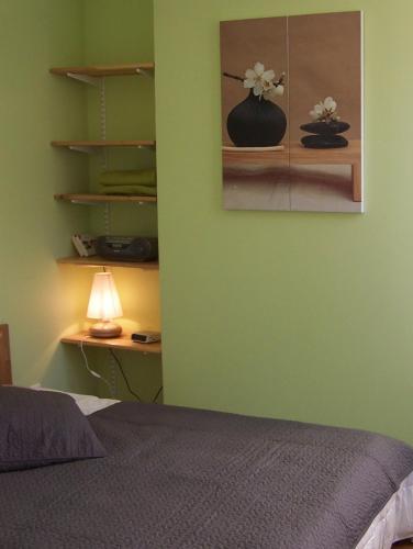 - une chambre dotée d'un mur vert avec un lit et une lampe dans l'établissement Gîte Mosaïque, à Arras