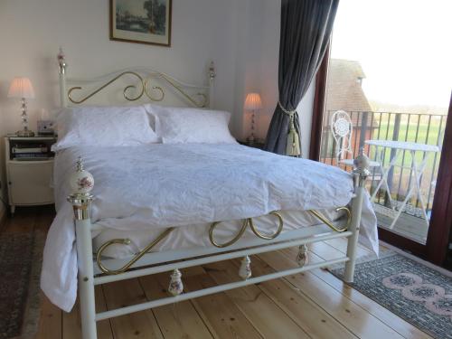 a bedroom with a white bed and a balcony at Mill House Bed & Breakfast in Sudbury