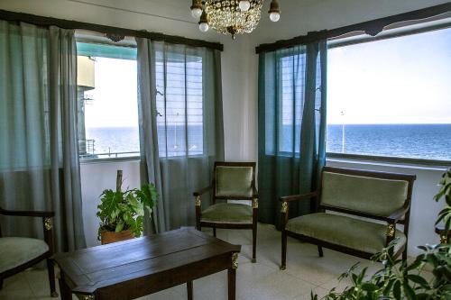 a living room with chairs and a table and windows at Bocamada in Havana