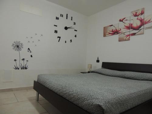 1 dormitorio con 1 cama y reloj en la pared en Casa Vacanze Mare, en Tortolì