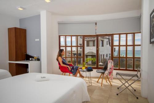 a woman sitting in a red chair in a bedroom at Hotel Volcano in Puerto Villamil
