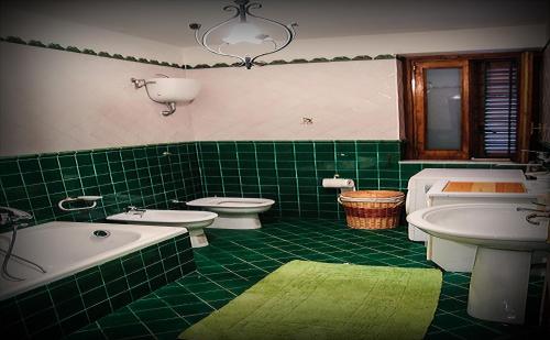 un bagno piastrellato verde con due servizi igienici, vasca e lavandino di Il Vigneto a Tramonti