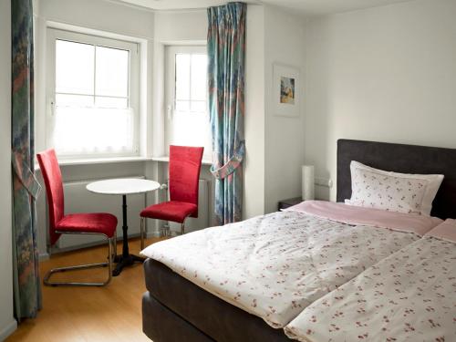 トラフェミュンデにあるSonnige Ferienwohnung am Meerのベッドルーム1室(ベッド1台、赤い椅子2脚付)