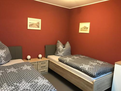 twee bedden in een kamer met rode muren bij Ferienwohnung Am Burgberg in Rübeland