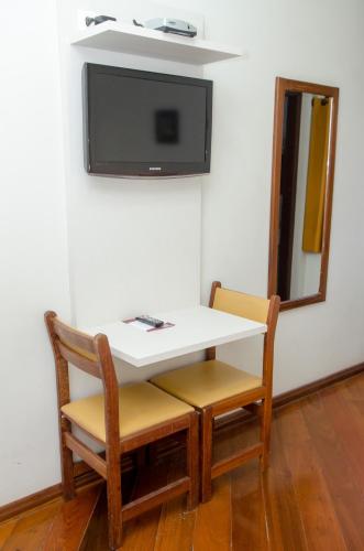 a white table and chairs with a tv on a wall at Samba Betim in Betim