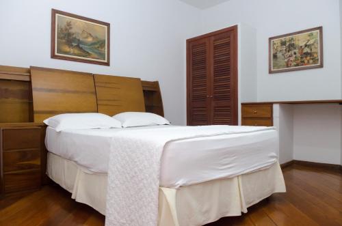 a bedroom with a large bed with white sheets at Samba Betim in Betim