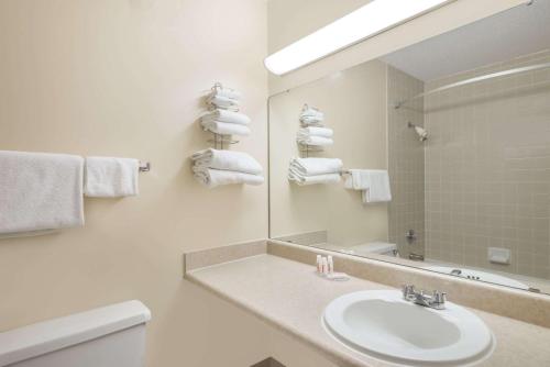 a white bathroom with a sink and a mirror at Ramada by Wyndham Watertown Thousand in Watertown