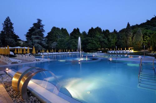 a large swimming pool with a fountain at night at Terme Preistoriche Resort & Spa in Montegrotto Terme