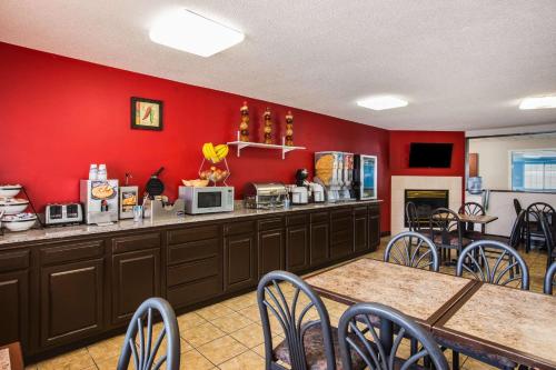 a restaurant with red walls and tables and chairs at Ramada by Wyndham Sioux Falls in Sioux Falls