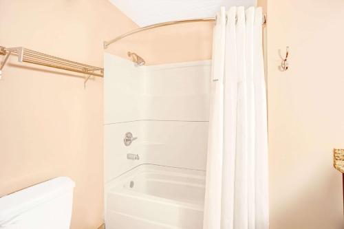 a bathroom with a white shower curtain and a toilet at Ramada by Wyndham Murfreesboro in Murfreesboro