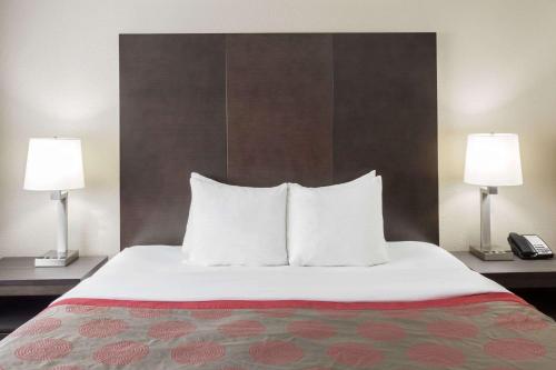 a hotel room with a bed with pillows and two lamps at Ramada by Wyndham Monterey in Monterey