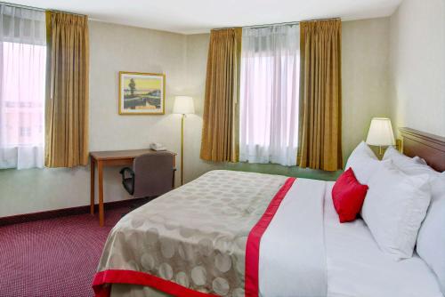 a hotel room with a bed and a desk at Ramada by Wyndham Hawthorne/LAX in Hawthorne