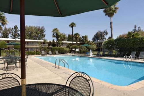 a large swimming pool with chairs and an umbrella at Ramada by Wyndham Sunnyvale/Silicon Valley in Sunnyvale