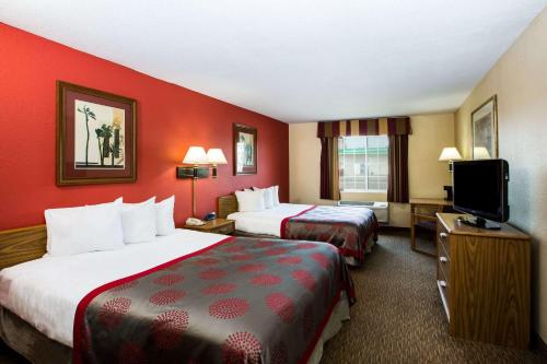 a hotel room with two beds and a flat screen tv at Ramada by Wyndham Sioux Falls in Sioux Falls